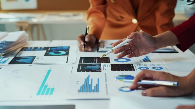 Businesswomen in the office are studying documents with charts and diagrams, working together to develop a business strategy