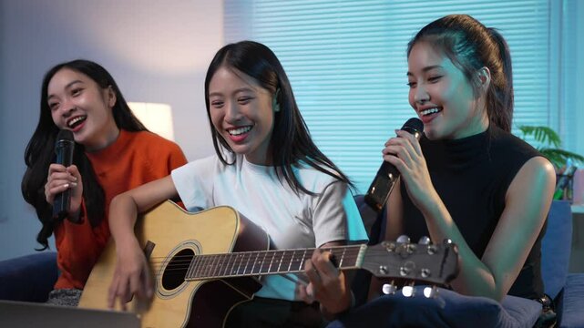 Three young women enjoy singing and playing guitar together, creating a joyful atmosphere filled with music and laughter