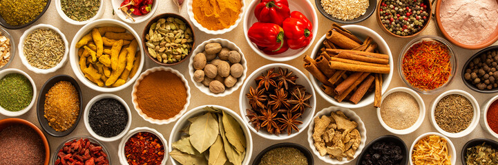 Collection of assorted spices and herbs spread on a beige background, blending exotic aromas and colors to inspire flavorful cooking, banner