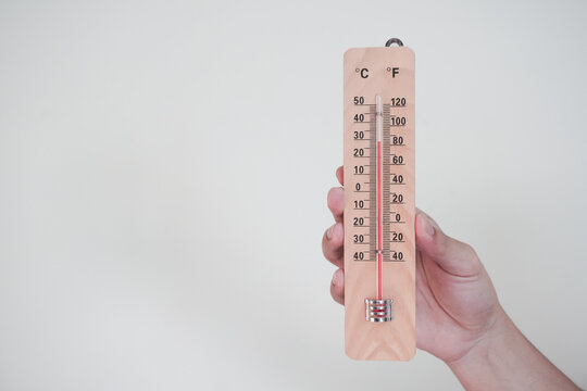 Hand holding classic room thermometer for checking temperature on white background isolation