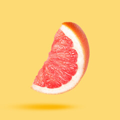 Sliced fresh juicy grapefruit in air on light orange background. Citrus fruit