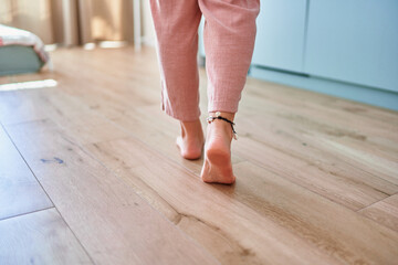 Barefoot female legs on comfortable heated warm tiles at home. Modern floor heating system in house