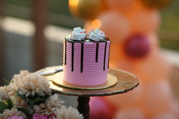 Beautifully decorated birthday cake on stand against blurred festive lights/
A pink cake, bridal shower cake, birthday cake,  Valentine's Day celebration, 