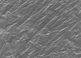 Сrumpled aluminum foil. Plastic transparent black cellophane background. Natural plastic texture surface.	