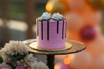 Beautifully decorated birthday cake on stand against blurred festive lights/
A pink cake, bridal shower cake, birthday cake,  Valentine's Day celebration, 