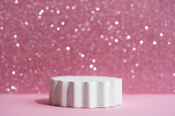 Geometric white podium on a pink shiny sparkling background for the presentation of a cosmetic product or gift. Premium scene. Showcase, display case.