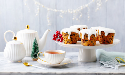 Christmas muffins, puddings with cup of tea on white plate. Grey background. Close up.