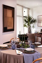 sophisticated table setting for dinner in a living room with candles in the center of the table
