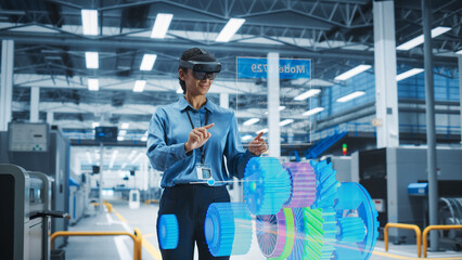 Female Engineer Wearing AR Headset in a High Tech Factory Uses Augmented Reality to Interact With...