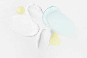 Cosmetic product textures featuring cream, gel in blue and transparent tones, and yellow drops on a light background