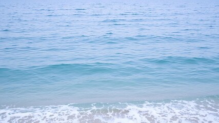 Fototapeta premium Serene ocean scene featuring a vast expanse of blue water with gentle waves lapping against the shore creating a foamy edge, beach shoreline, blue ocean, reflective surface
