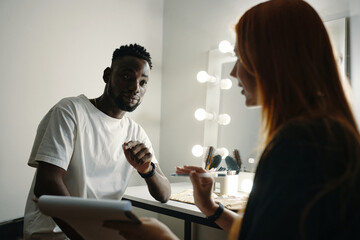 Discussing important business aspects in modern office setting with makeup desk and lighted mirror in background creating engaging atmosphere