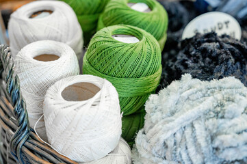 Skeins of thread close-up concept handicrafts leisure time handmade. Needlework, macrame, knitting. Yarn and threads of bright colors in a wicker basket on a wooden background. 