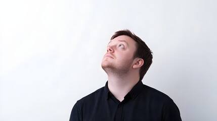 Obraz premium Young Caucasian man in black shirt looking upwards.