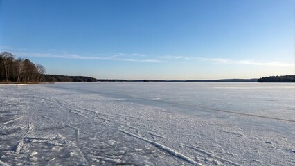 A frozen lake stretches out into the distance like a sheet of polished silver reflecting the pale blue sky above, landscape, ice