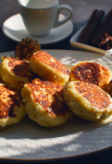 Vanilla nut cottage cheese pancakes ( syrniki or curd fritters) decorated with walnuts on white plate in sunny morning. High-protein breakfast ideas.