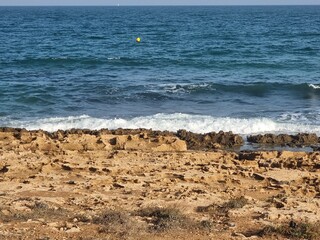 Blick auf das Meer mit wellenumspülten Felsplatten im Vordergrund. Der Horizont erstreckt sich...