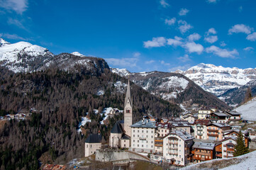 Obraz premium Dolomites, Italy. Pieve di Livinalongo village with church and houses near Arabba ski resort. Sella mountain massif in the background on the right