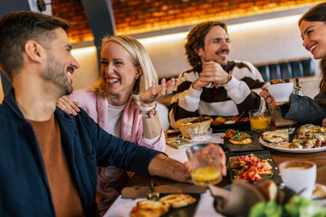 Friends gathered in a restaurant to eat delicious food, talk, drink and hang out.