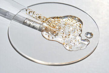 Transparent gel with gold flakes in petri dish on white background for skincare and beauty concepts