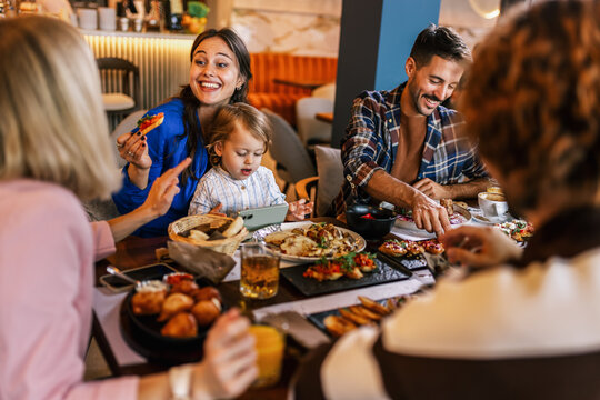 Family and friends gathered in a restaurant to eat delicious food, talk, drink and hang out. - Powered by Adobe