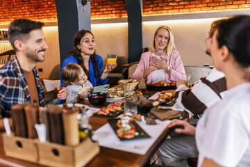 Family and friends gathered in a restaurant to eat delicious food, talk, drink and hang out.