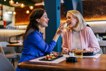 Smiling lesbian couple feeding to each other at restaurant