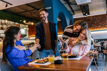 Friends gathered in a restaurant to eat delicious food, talk, drink and hang out.