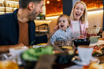 Family of three eating in a restaurant delicious food. Food and drink concept.