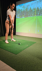 Woman playing golf on screen and golf simulator concept