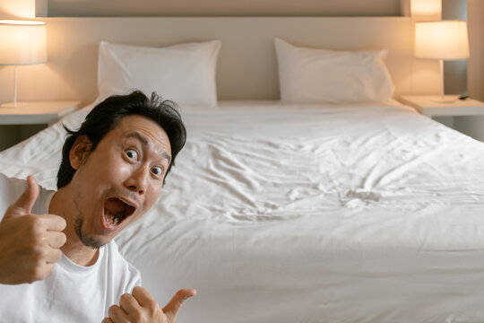 Funny wow face asian man feeling amazing and present the bedroom of hotel.