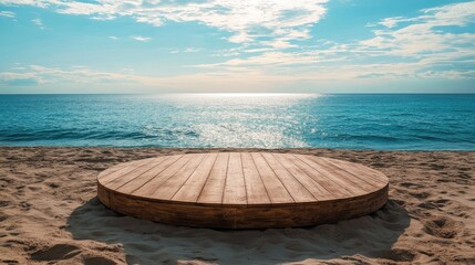 Circular wooden platform on sandy beach with ocean view under a blue sky, featuring gentle waves and soft clouds in a tranquil natural setting.