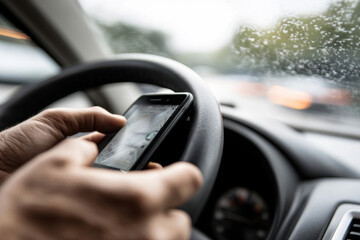 Man driver is using smartphone while driving car. Dangerous behavior, accident risk, driver distraction concept