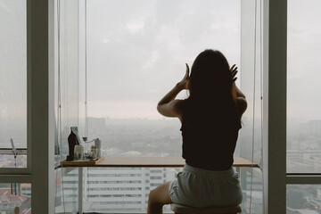 Asian woman relaxed at her windows apartment, enjoy the view and time.