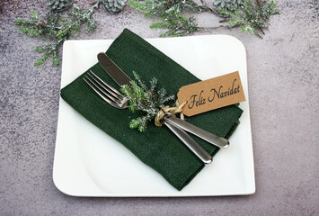 Feliz Navidad: Mesa con platos, cubiertos, adornos navideños y una tarjeta con la inscripción...