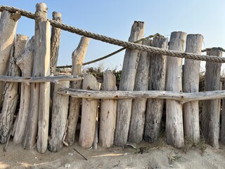 vacation theme by the beach with a fence made of old driftwood and rope with blue sky as background