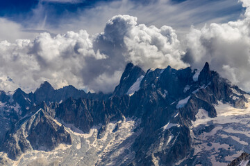 Obraz premium Snow mountains view in the Alps from Aiguille du Midi summit. Rocky mountain peaks scene covered with snow and ice of huge alpine glacier on the massive du Mont Blanc range in Chamonix
