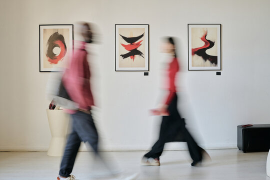 People walking through an art gallery, admiring contemporary paintings hanging on wall, modern abstract art and clean, minimalist interior create a calm atmosphere