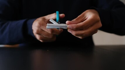  Close-up of hands cutting a cigarette with scissors. Quitting smoking concept.