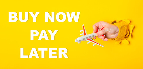Hand holding a toy airplane with the words Buy Now Pay Later written below it