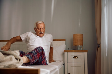 Senior man getting out of  bed in morning.