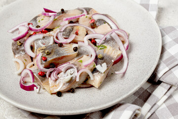 salted herring, with spices and red onion, sliced fillet, on a plate, top view,