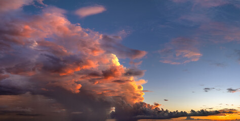 Colorful sunset sky with setting sun behind vivid orange and yellow clouds