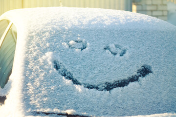 A smile is gently depicted on the snow cover, creating a playful mood and a contrast between cold...