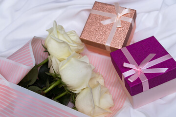 Postcard. White roses and gifts on a white, fabric background.