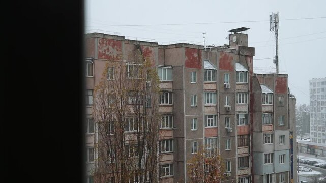 view from window on snowy winter weather in city. Panel high-rise shabby house in soviet style old residential area in ukraine. Architecture of eastern europe and soviet union
