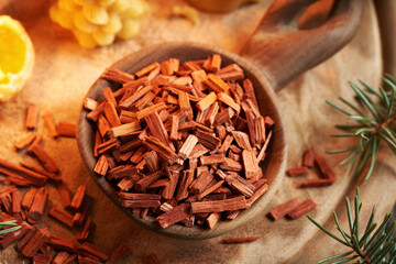 Closeup of red sandalwood chips on a wooden spoon with beeswax candles
