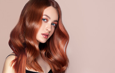 Beauty redhead girl with long and shiny wavy red hair . Beautiful woman model with curly hairstyle .
