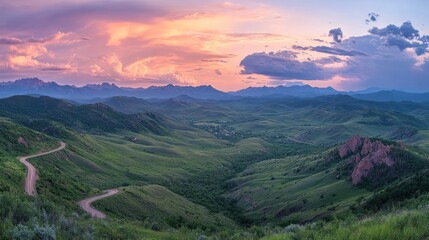 Scenic mountain range landscape with a winding road and vibrant sunset sky.