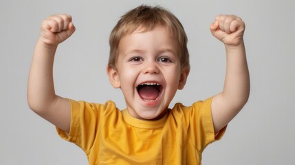 A joyful boy in a yellow t-shirt celebrates, fists raised in pure happiness